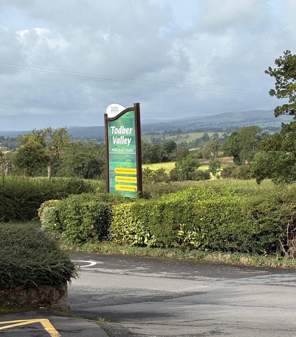 The Todber Valley Holiday Park entrance sign with countryside behind
